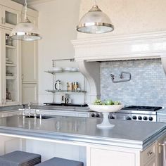 a large kitchen with stainless steel counter tops and stools in front of the island