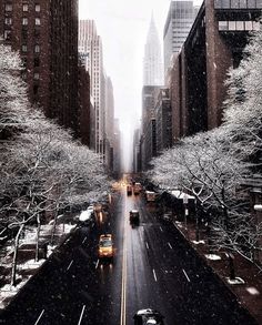 a city street filled with lots of traffic covered in snow and surrounded by tall buildings