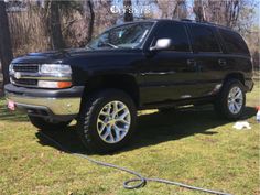 a black suv is parked in the grass with its hose hooked up to it's tire