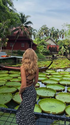 a woman standing on a bridge looking at lily pads