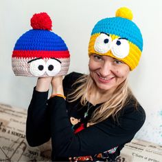 a woman holding up two crocheted hats that look like the characters from the simpsons