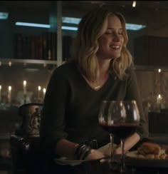 a woman sitting at a table with a glass of wine and food in front of her