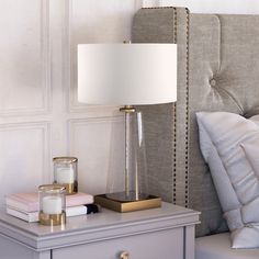 a nightstand with a lamp on it next to a bed