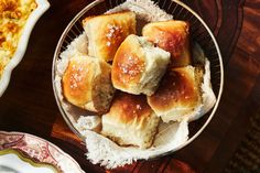 bread rolls are piled on top of each other in a bowl next to another dish