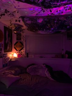 a bedroom with purple lighting and decorations on the ceiling, bedding is unmade