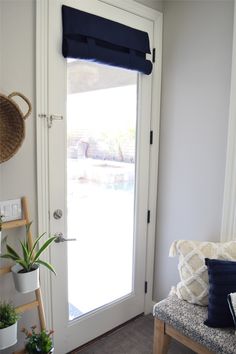 a room with a door and some plants on the bench in front of the door