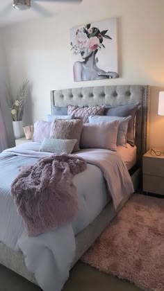 a bedroom with a large bed covered in pink and gray blankets, pillows and throw pillows