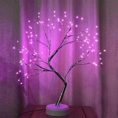 a small tree with purple lights in front of a curtain