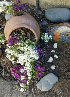 a potted planter filled with purple and white flowers sitting on top of dirt