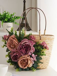 a basket filled with flowers sitting on top of a table next to a cup and saucer