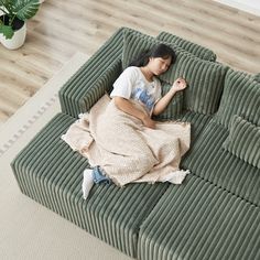 a woman laying on top of a green couch