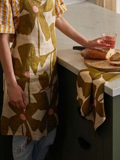 a woman standing in front of a counter cutting food on a wooden board with a knife