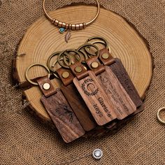 four wooden keychains sitting on top of a piece of wood