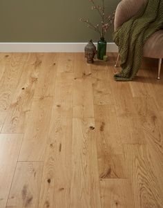 a living room with hard wood flooring and a green blanket on the chair next to it