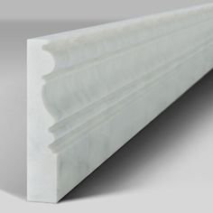 an image of a white plastic profile for a wall or flooring piece that looks like it has been cut in half