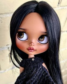 a close up of a doll with long black hair and blue eyes wearing a dress