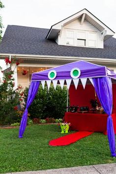 a purple tent with green eyes on it in front of a house