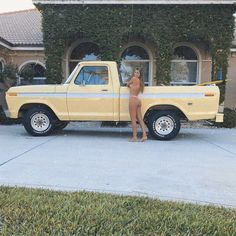 a nude woman standing next to a yellow truck