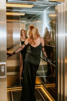 two women in black dresses are entering an elevator