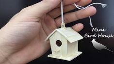 a hand holding a small birdhouse ornament in it's left hand