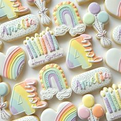 decorated cookies with rainbows, clouds, and balloons are arranged on a white surface