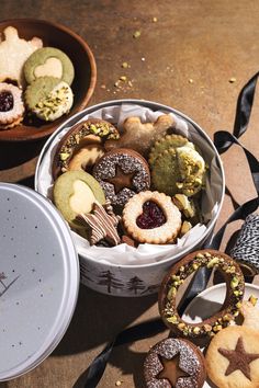 some cookies and pastries are in a tin on the table next to other treats