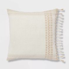 an embroidered pillow with tassels on the front and back, in white linen