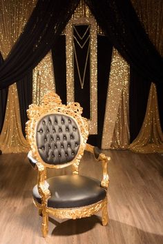 a fancy chair sitting on top of a hard wood floor next to a black curtain