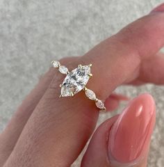 a woman's hand holding a ring with a diamond on it and a pink manicure