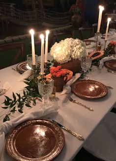 a table set with plates, candles and flowers on it for a formal dinner or party