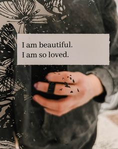 a person holding a piece of paper with the words i am beautiful, i am so loved