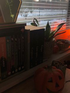 a window sill filled with books next to a pumpkin