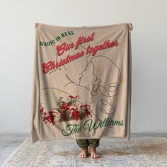 a woman standing on top of a rug holding up a christmas blanket that says, magic is real