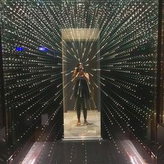 a man standing in front of a mirror with lights all around him and his reflection