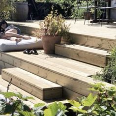 a woman laying on top of a bed in the middle of some steps next to a potted plant