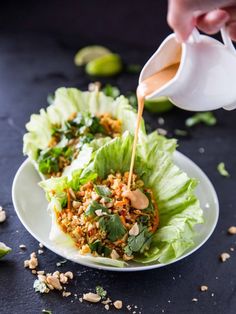 lettuce leaves with dressing being drizzled onto them on a plate