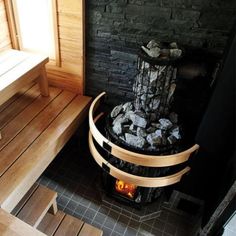 a fire place in the middle of a room with wooden floors and walls, next to a bench