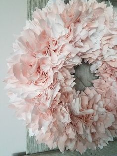 a pink wreath hanging on the side of a wooden frame in front of a white wall