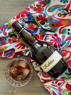 a bottle of alcohol sitting on top of a table next to a glass filled with ice