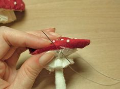 someone is working on something that looks like mushrooms with red and white dots, while they are being sewn together