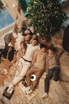 a group of people laying on the floor next to a christmas tree