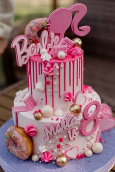 a pink and white birthday cake with donuts