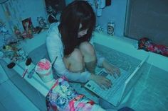 a woman is sitting in the bathtub on her laptop