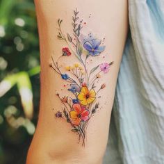 a woman's arm with flowers on it and watercolors in the background