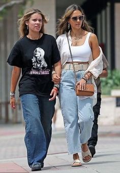 two women walking down the street with one carrying a purse and another holding a handbag