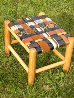 a wooden stool made out of strips of wood and leather on the grass with green grass in the background