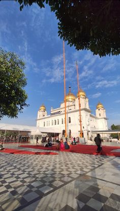 people sitting on the ground in front of a large white building with gold trimmings