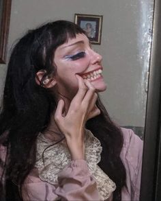 a woman with long black hair and blue eyes is posing for the camera in front of a mirror