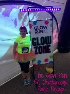 a woman standing in front of a glow run sign