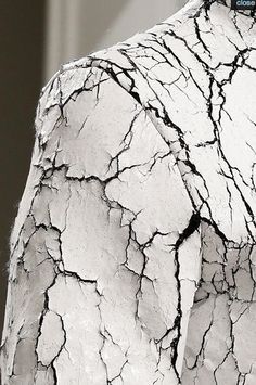 the back of a man's shirt covered in cracked white and black paint,